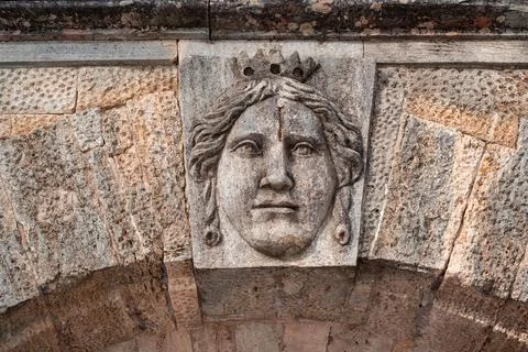 A stone face above the arch. The expression of the face above the gate. Stock Photos