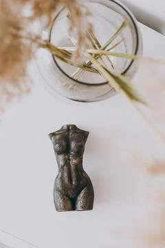 A stone figurine in the shape of a female figure stands on the table as decor Stock Photos