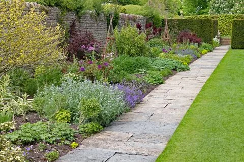 Stone flag path in front of a herbaceous border at an English country garden Stock Photos