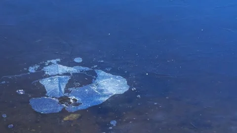 Stone flies onto thin ice, breaks it and leaves large splashes and cracks. Stock Footage 297659539