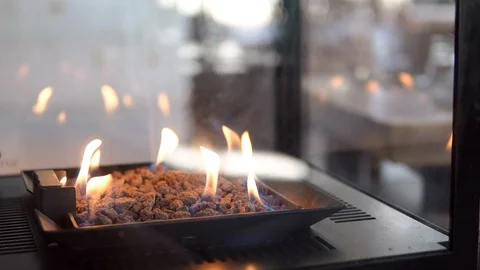 Stone gas fire pit with flames in modern fireplace in the restaurant 스톡 동영상 98480583