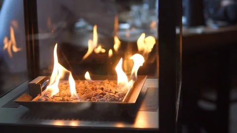 Stone gas fire pit with flames in modern fireplace in the restaurant 스톡 동영상 98481483