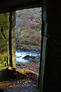 Stone gate of old abandoned mill through which the stream of a river Stock Photos