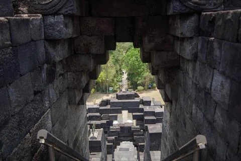 Stone gateway frames distant Borobudur stupas and terraces within the ancie.. Фото