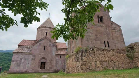 Stone Goshavank Monastery ruins with domes, framed by leaves 库存影片 341736494