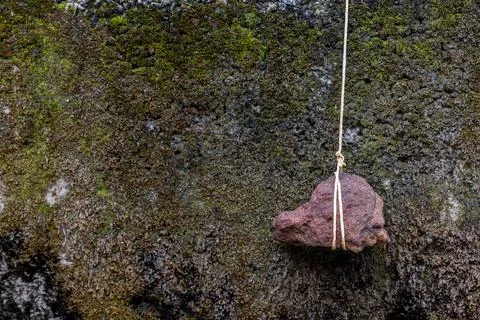 Stone hanging by a string. A stone tied to a rope. Foto stock
