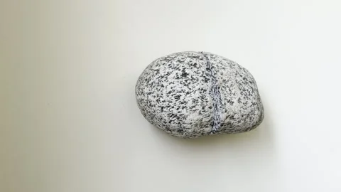 A stone hangs on a light beige wall 库存影片 336099007