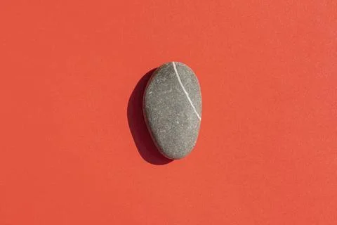 A stone with a hard shadow on a red background Stock Photos