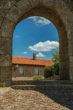 Stone house seen through wall gate arch Stock Photos