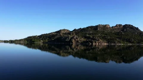 Stone island in a lake. Clear reflection. A girl in a white dress on a cliff. Stock Footage 142247369