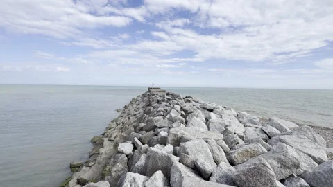 Stone jetty extending into calm sea panning Stock Footage 338135098