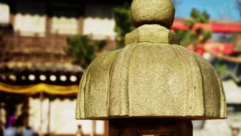 Stone lantern in a garden with traditional structures in the background Stock Footage 344860741