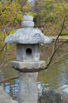 Stone lantern situated beside a tranquil pond in a Japanese garden Stock Photos