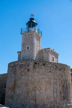 Stone lighthouse tower above round fort wall Фото