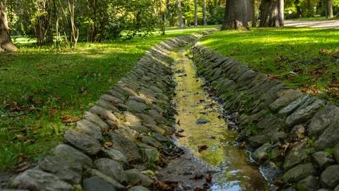 Stone Lined Drainage Canal Through a Lush Green Landscape Stock Photos