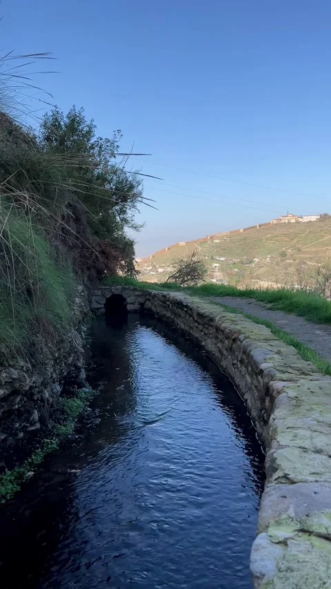 Stone-lined water channel with view of Sacromonte hillside, Granada Stock Footage 344411999