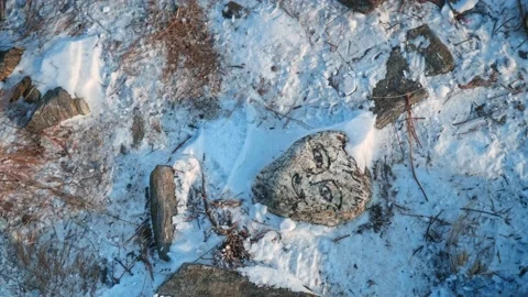 A stone lying in the ground with a painted human face near a Buddhist monument Stock Footage 228883276