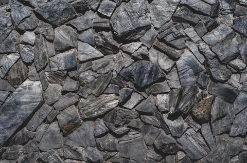 Stone masonry wall, rough layered black sandstone, uneven grungy vintage back Stock Photos