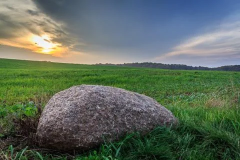 Stone in the meadow during sunset Stock Photos