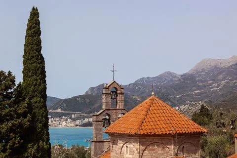 A stone monastery with bells against the background of the sea and mountains. Stock Photos