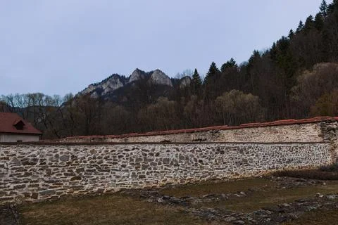 Stone Monastery Wall with Mountain Peaks and Forest Background Foto stock