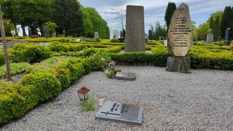 Stone monuments and grave markers in a cemetery with green hedges Stock Photos