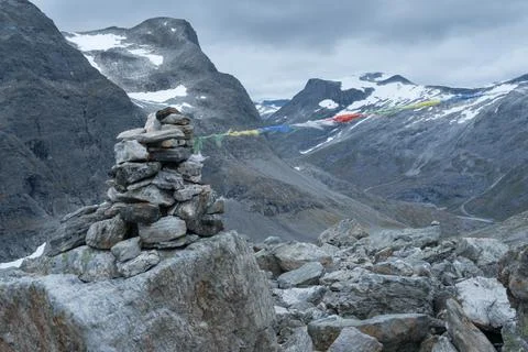 Stone mound with dramatic mountain scenery in the back on the hiking trail to Stock Photos