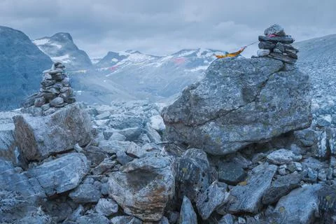 Stone mound with dramatic mountain scenery in the back on the hiking trail to Stock Photos