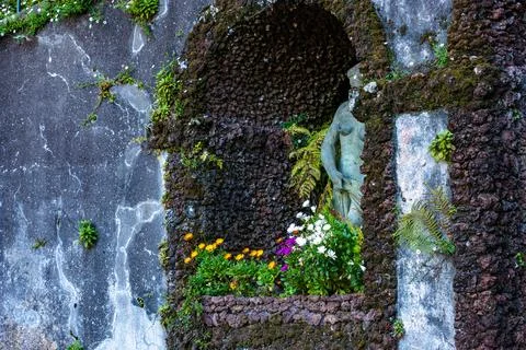 Stone niche with classical statue and flowers in Madeira garden Stock Photos