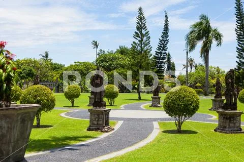 A stone path and shrubs of various shapes in the exotic Park Stock Photos