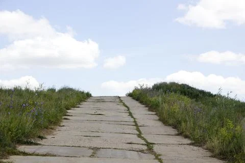 Stone path on the dunes with blue sky and clouds in the background Stock Photos