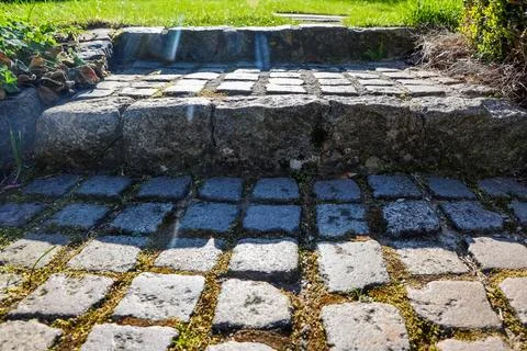 Stone path steps ascending into green lawn with sunlight Stock Photos