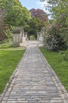 Stone path winds through lush green gardens Stock Photos