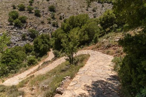 Stone pathway winds through lush vegetation towards the Dikteon cave in Crete Stock Photos