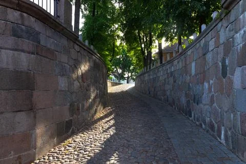Stone paved pathway between curved walls Stock Photos
