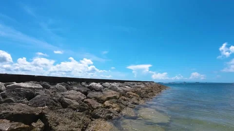 Stone pier on a calm beach with clear blue sky Stock Footage 237934719