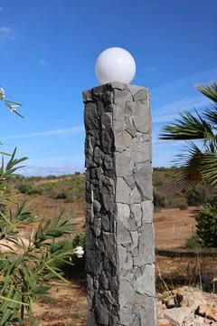 Stone pillar with a white globe light against a bright blue sky Stock Photos