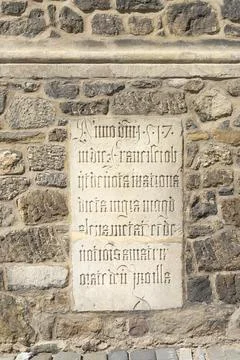 A stone plaque with Gothic script is set into a stone wall. in Brno, Czech .. Stock Photos