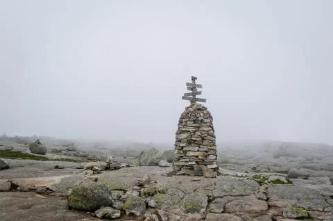 Stone pyramide with hiking path route sign in the foggy weather Stock Photos