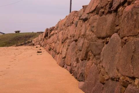 Stone Retaining Wall Lining Edge of Beach Sand Stock Photos