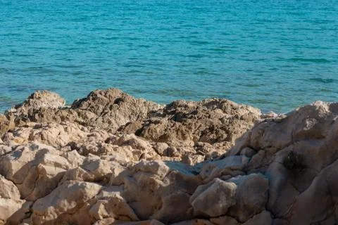 Stone rocks on the shore of split, bright blue warm sea water Stock Photos