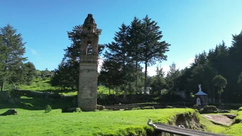 Stone ruin tower beside small garden monuments on a lawn Stock Footage 346015738