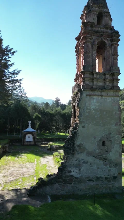 Stone ruin tower tilting down to a small garden gazebo Stock Footage 346015787