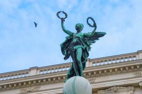 Stone rusty statue with two wreath in arms and with bird in clear sky in Vien Stock Photos