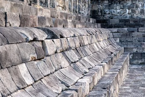 Stone seating structure at Borobudur Temple with worn, curved blocks and an.. Stock Photos