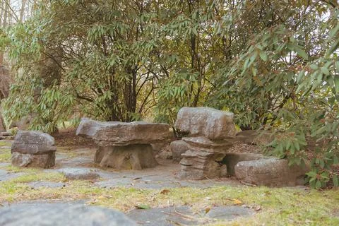Stone seating structures and rock stacks sit on grass 스톡 사진
