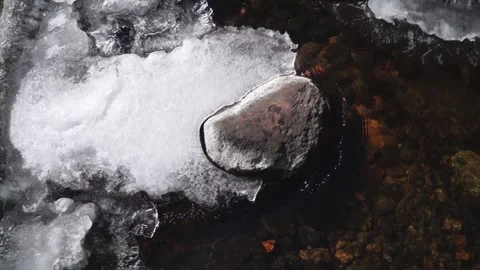 Stone in a shallow river. Stone in the stream. Ice on the river Stock Footage 172000258