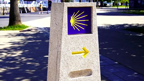 Stone sign with Scallop Shell and Yellow Arrow on the way of Camino de Santiago Stock Footage 202031869