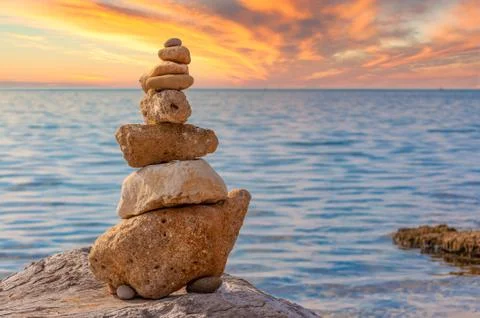 Stone stacking on the coast at sunset with dramatic sky Stock Photos