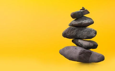 Stone-stacking or rock balancing with yellow background. Stock-Fotos